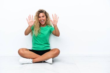 Yerde oturan kıvırcık saçlı kız parmaklarıyla 10 'a kadar sayıyor.