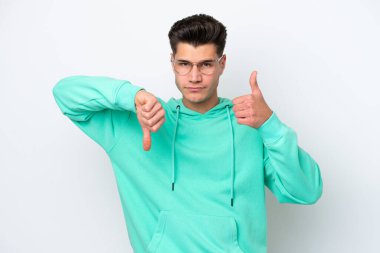 Beyaz fırında izole edilmiş beyaz yakışıklı beyaz adam iyiye kötüye işaret veriyor. Evet ya da hayır arasında kararsız