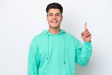 Beyaz fırında izole edilmiş yakışıklı beyaz bir adam en iyinin işareti olarak parmağını kaldırıyor ve gösteriyor.