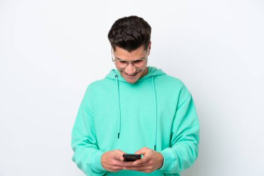 Beyaz bakkalda izole edilmiş yakışıklı beyaz bir adam cep telefonuyla mesaj yolluyor.