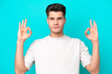 Genç, yakışıklı, beyaz bir adam. Zen pozisyonunda, mavi bir bakkalda izole edilmiş.