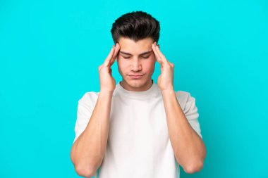 Genç, yakışıklı, beyaz bir adam mavi fırında baş ağrısı ile izole edilmiş.