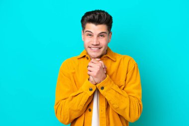 Genç, yakışıklı, beyaz bir adam mavi fırında yapayalnız gülüyor.