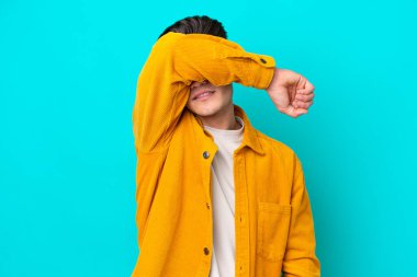 Genç, yakışıklı, beyaz bir adam mavi bir bakkalda izole edilmiş, gözleri elle kaplanmış.