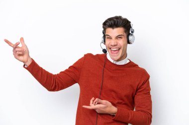 Tele pazarlamacı beyaz arka planda izole edilmiş bir kulaklıkla çalışan beyaz bir adam gitar hareketi yapıyor.