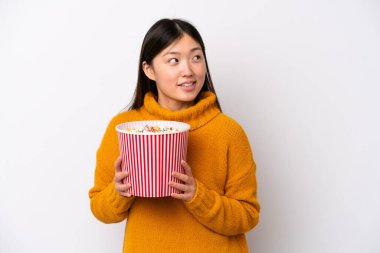 Beyaz arka planda izole edilmiş genç bir Çinli kadın elinde koca bir kova patlamış mısır tutuyor.