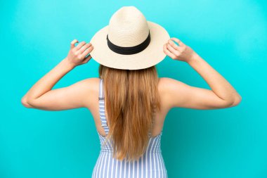 Mavi arka planda, mayo giymiş ve arka planda kalan genç bir kadın.