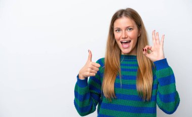 Beyaz arka planda izole edilmiş genç beyaz bir kadın tamam işareti ve baş parmak hareketi gösteriyor.