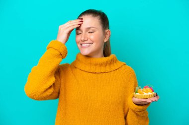 Mavi arka planda izole edilmiş tart tutan beyaz bir kadın bir şey fark etti ve çözüme niyetlendi.