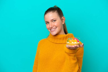 Mavi arka planda izole edilmiş bir tart tutan beyaz bir kadın.