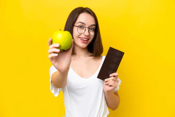 Young Ukrainian Woman Isolated Yellow Background Taking Chocolate Tablet One — Fotografia de Stock