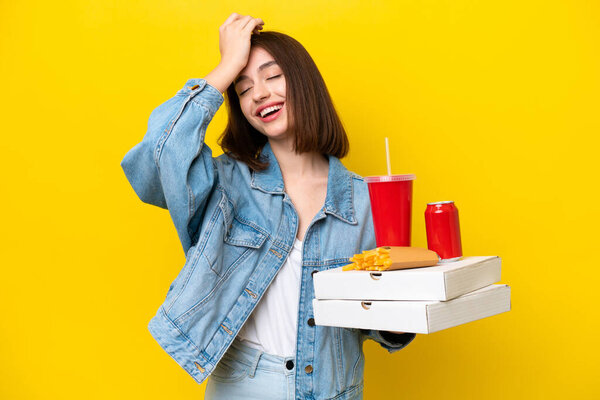 Young Ukrainian woman holding fast food isolated on yellow background has realized something and intending the solution