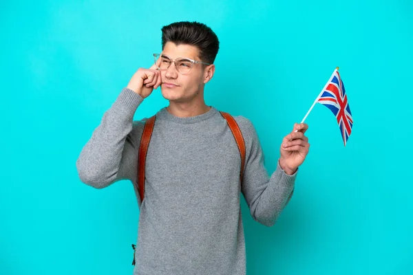 青い背景に英国の旗を掲げた若い白人男性は疑問と思考を持っています — ストック写真