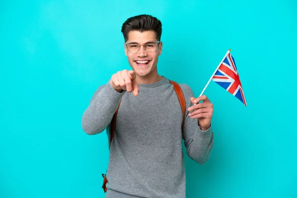 青い背景に隔離された英国の旗を持っている若い白人男性は驚いて前を向いて — ストック写真