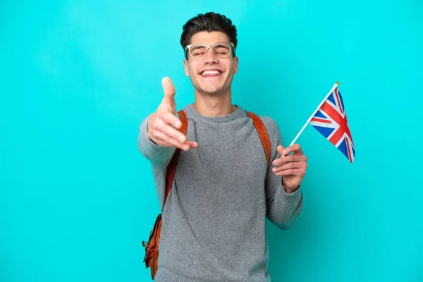 青の背景で隔離された英国の旗を持っている若い白人男性は良い取引を閉じるために握手 — ストック写真