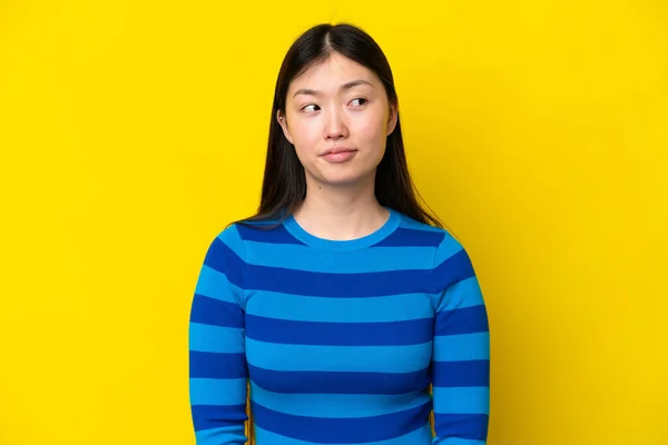 Young Chinese Woman Isolated Yellow Background Making Doubts Gesture Looking — 스톡 사진