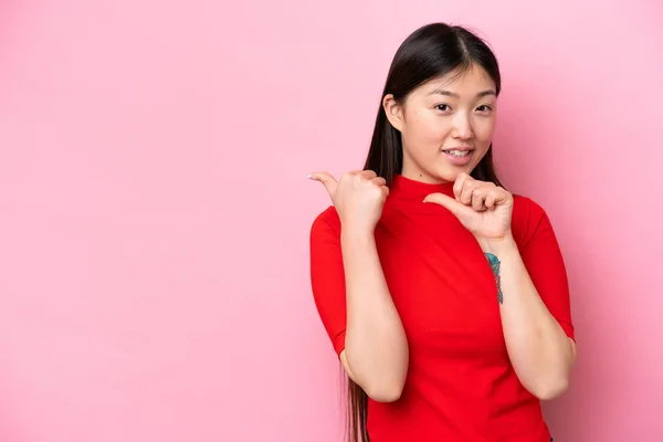 Молода Китайка Ізольована Рожевому Фоні Вказує Збоку Щоб Представити Продукт — стокове фото