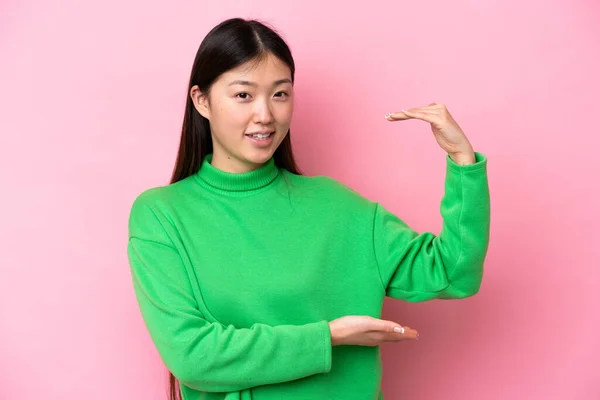 在粉色背景上被隔离的年轻中国女人拿着复制空间插入广告 — 图库照片