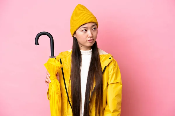 Young Chinese Woman Rainproof Coat Umbrella Isolated Pink Background Looking — Stockfoto