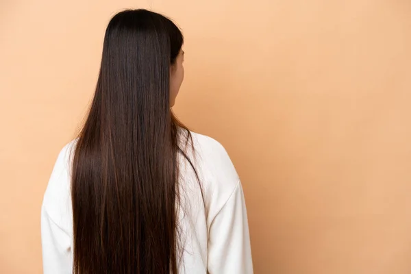 Young Chinese Woman Isolated Beige Background Back Position Looking Side — Stock Photo, Image