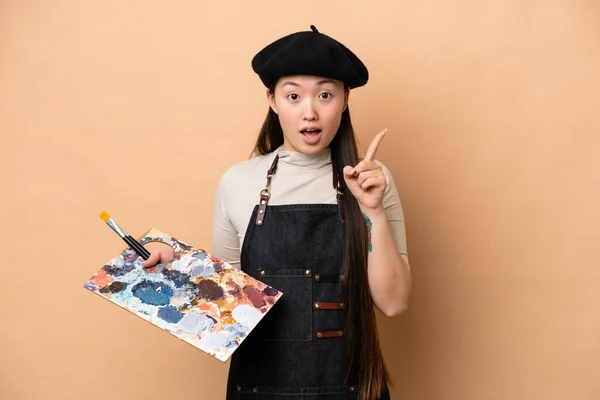 年轻的中国油漆工女人因米色背景而被隔离 想在举手表决的同时实现这个解决方案 — 图库照片