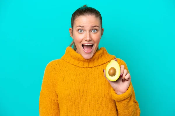 Young Caucasian Woman Holding Avocado Isolated Blue Background Surprise Shocked — Stok fotoğraf