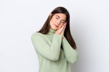 Beyaz arka planda izole edilmiş genç Brezilyalı kadın uyku jesti yapıyor.