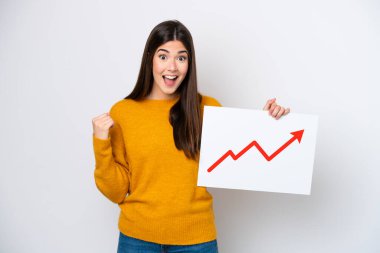 Beyaz arka planda izole edilmiş genç Brezilyalı kadın elinde büyüyen bir istatistik okuyla bir işaret tutuyor ve zaferi kutluyor.