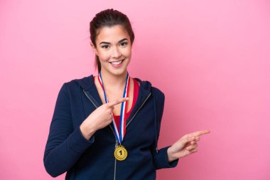Pembe arka planda madalyalı genç Brezilyalı sporcu kadın şaşırmış ve işaret ediyor.