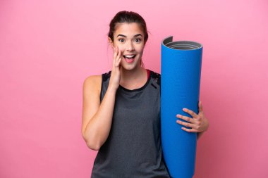 Brezilya 'lı genç sporcu kadın yoga derslerine gidiyor. Elinde pembe bir arka planda, şaşırmış ve şok olmuş bir yüz ifadesi olan bir minder tutuyor.