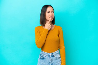 Mavi arka planda izole edilmiş genç beyaz kadın gergin hareketler yapıyor.