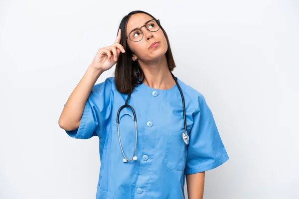 若い外科医の女性は疑問を持ち 顔の表情を混乱させる白い背景に隔離 — ストック写真