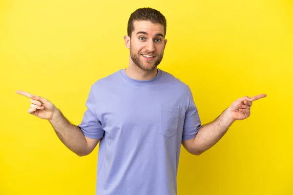 Handsome Blonde Man Isolated Yellow Background Pointing Finger Laterals Happy — Zdjęcie stockowe