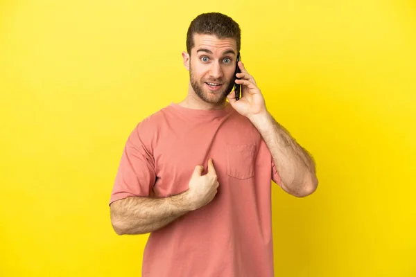 Handsome Blonde Man Using Mobile Phone Isolated Background Surprise Facial — Zdjęcie stockowe