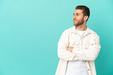 Yakışıklı sarışın adam mavi arka planda mutlu ve gülümsüyor.