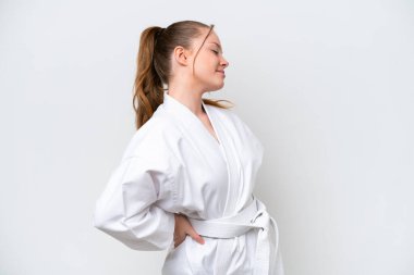 Beyaz arka planda karate yapan genç beyaz bir kız gayret gösterdiği için sırt ağrısı çekiyor.