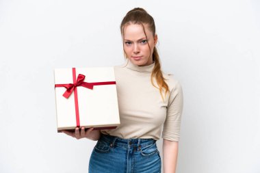 Beyaz arka planda hüzünlü bir ifadeyle izole edilmiş bir hediye tutan beyaz bir kadın.