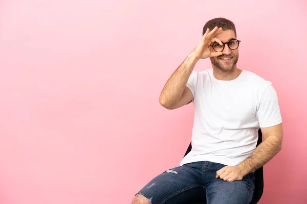 Young Man Sitting Chair Isolated Pink Background Showing Sign Fingers — Stok fotoğraf
