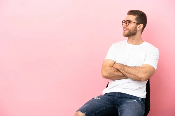 Joven Sentado Una Silla Sobre Fondo Rosa Aislado Feliz Sonriente — Foto de Stock