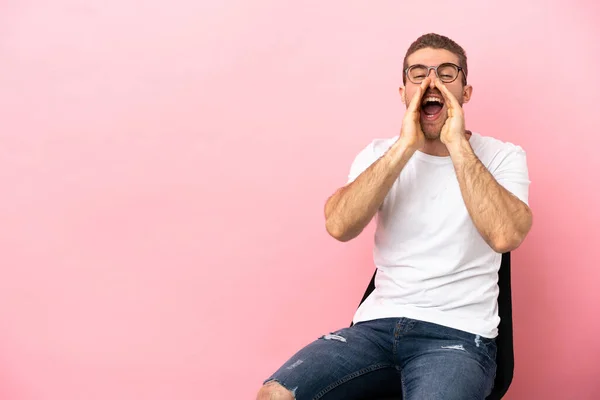 Young Man Sitting Chair Isolated Pink Background Shouting Announcing Something — 스톡 사진