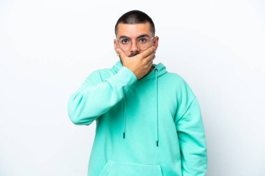 Beyaz arka planda izole edilmiş beyaz tenli genç bir adam ağızı eliyle kapatıyor.