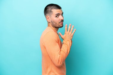 Kafkasyalı genç adam mavi arka planda bir şeyler planlıyor.
