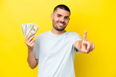 Genç beyaz adam, sarı arka planda izole edilmiş bir şekilde çok para alıyor.
