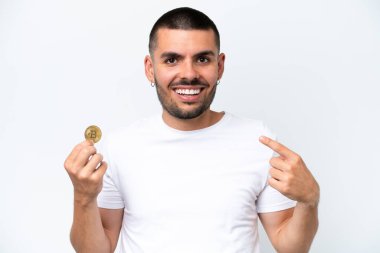 Young caucasian man holding a bitcoin isolated on white background giving a thumbs up gesture