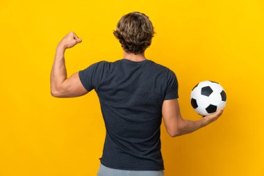 İngiliz adam futbol topuyla izole edilmiş sarı arka plan