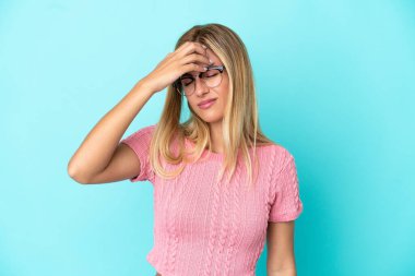 Sarışın Uruguaylı kız mavi arka planda baş ağrısı ile izole edilmiş.