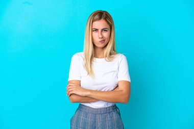 Sarışın Uruguaylı kız mutsuz bir ifadeyle mavi arka planda izole edilmiş.