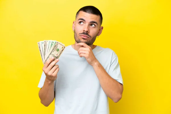 Jonge Blanke Man Neemt Veel Geld Geïsoleerd Gele Achtergrond Kijkt — Stockfoto