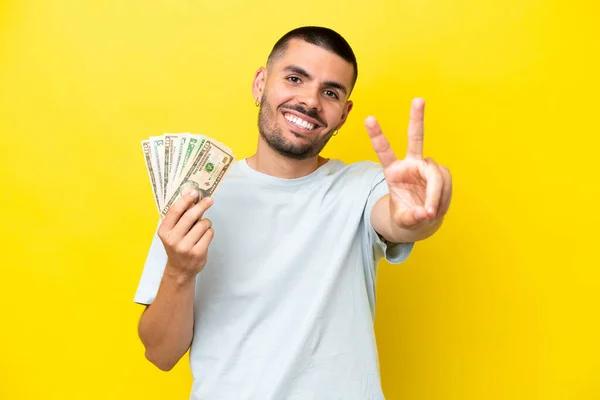 Jovem Caucasiano Tomando Monte Dinheiro Isolado Fundo Amarelo Sorrindo Mostrando — Fotografia de Stock