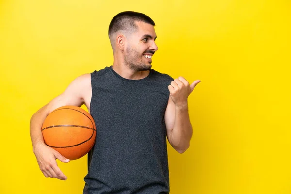 Young Caucasian Basketball Player Man Isolated Yellow Background Pointing Side — Foto de Stock